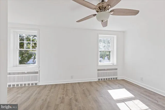 an empty room with a window and a ceiling fan