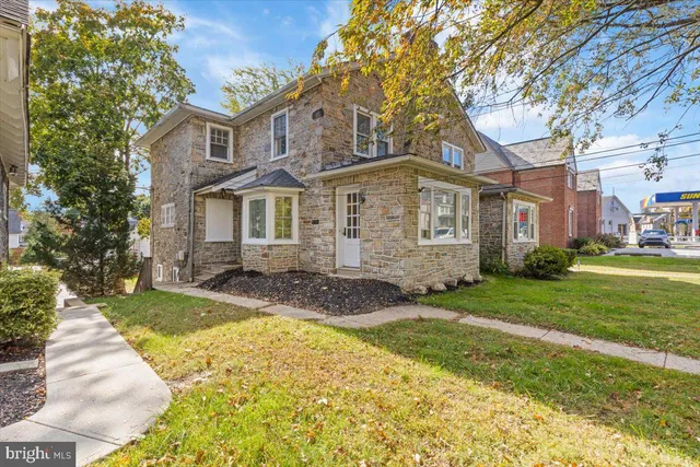 a front view of a house with a garden and trees