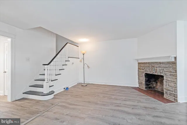 a view of an empty room with wooden floor fireplace and a window