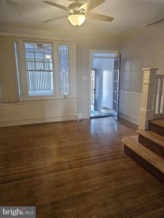 a view of an empty room with window and wooden floor