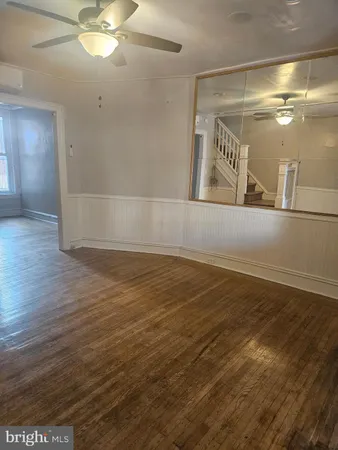 en empty room with wooden floor and fan
