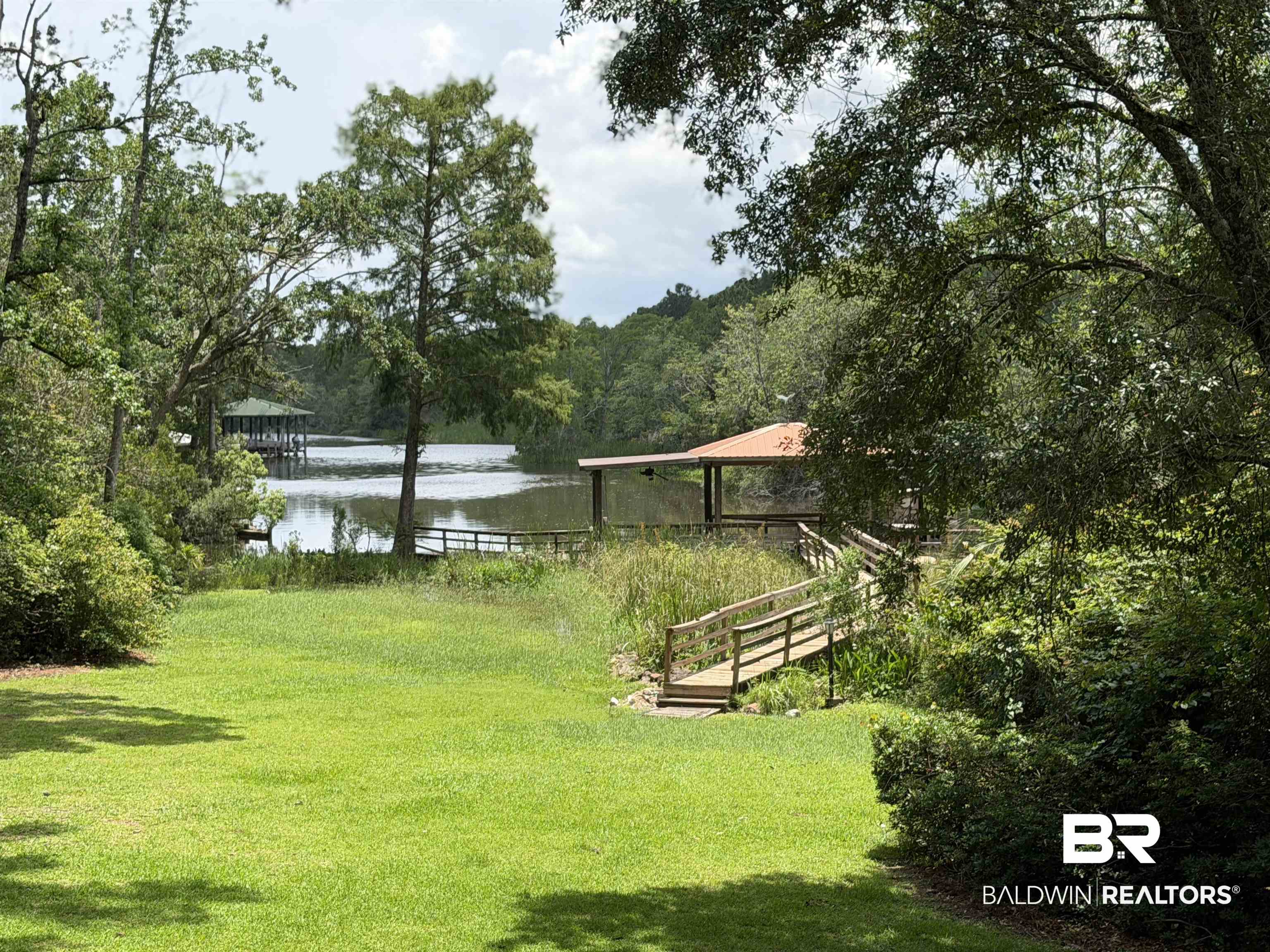3500 Venetia Road Mobile, AL 36605 - Photo 53 of 56 Waterfront property featuring a covered dock, a private wooden walkway, and a manicured lawn