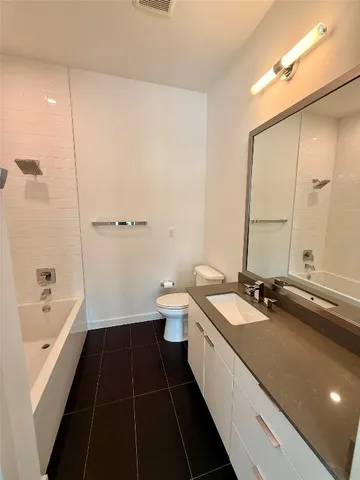 a bathroom with a double vanity sink a toilet a bathtub and shower