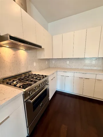 a kitchen with granite countertop wooden cabinets and a stove top oven