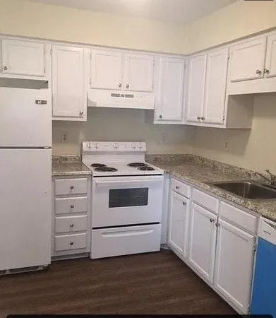 a kitchen with granite countertop white cabinets and white appliances