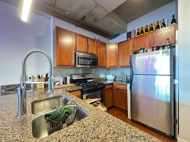 a kitchen with stainless steel appliances granite countertop a refrigerator sink and stove