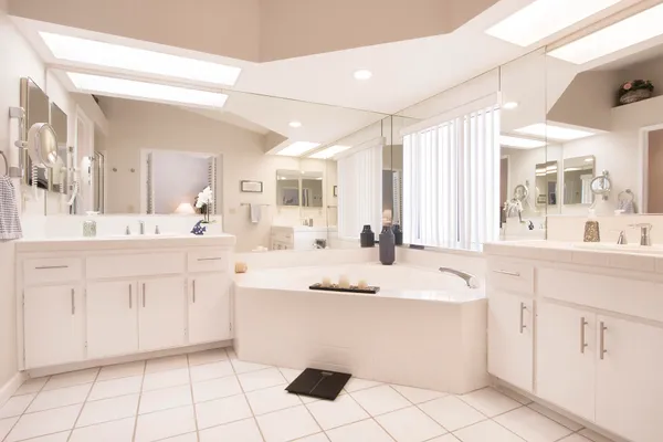 a bathroom with a sink vanity granite tub shower and a mirror