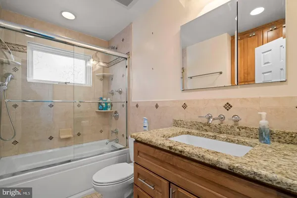 a bathroom with a granite countertop sink a toilet and shower