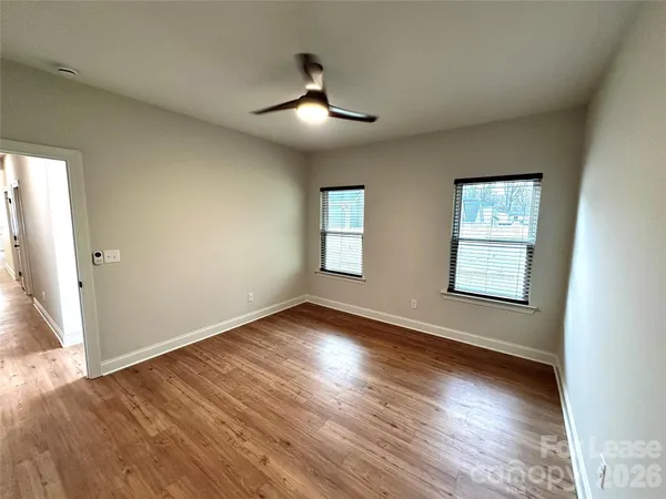 an empty room with wooden floor chandelier and windows