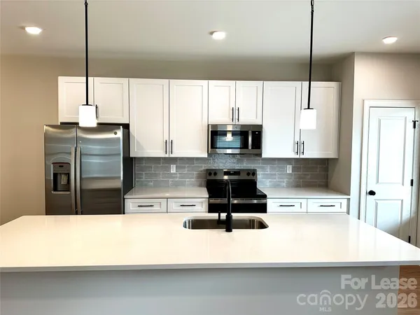 a kitchen with kitchen island a counter top a stove a fridge and a sink