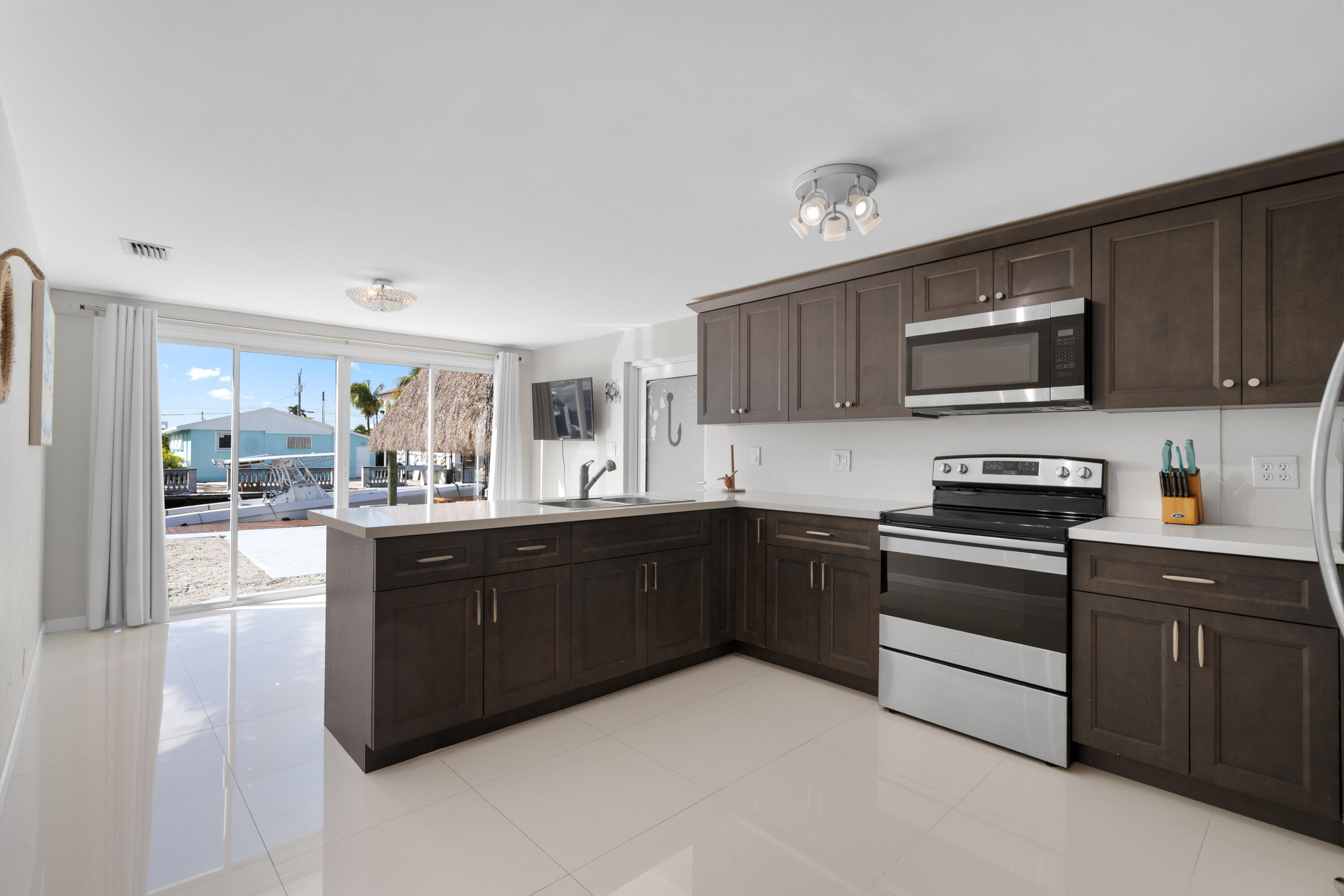 314 Windley Road Key Largo, FL 33037 - Photo 13 of 32 a kitchen with stainless steel appliances granite countertop a stove top oven a sink dishwasher and a microwave oven on the blue kitchen countertops