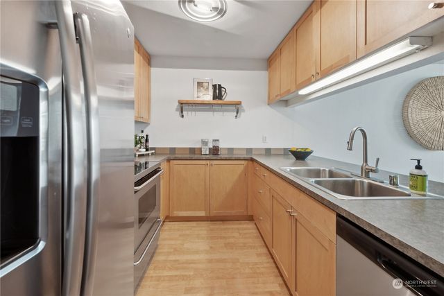 a kitchen with stainless steel appliances granite countertop a refrigerator a sink and white cabinets