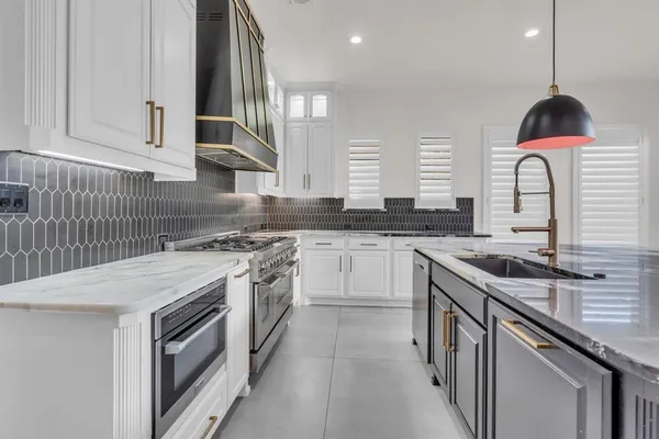 a kitchen with stainless steel appliances granite countertop a sink a stove and a wooden floors