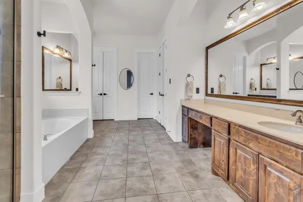 a spacious bathroom with a granite countertop sink a mirror a vanity and bathtub