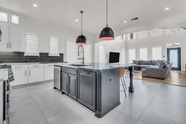 a kitchen with stainless steel appliances granite countertop a sink a stove and a view of living room with a flat screen tv