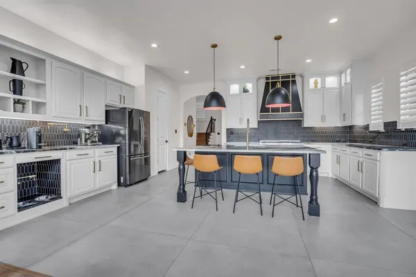 a kitchen with stainless steel appliances kitchen island granite countertop a table chairs microwave and sink