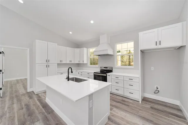 a kitchen with a sink a stove a refrigerator and white cabinets