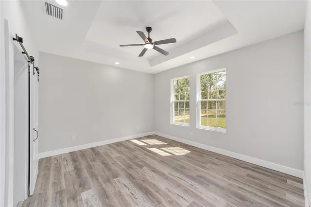 a view of empty room with wooden floor and fan