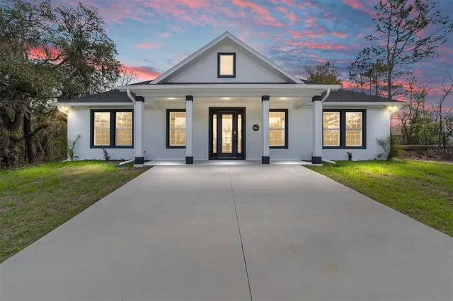a front view of a house with a yard and potted plants