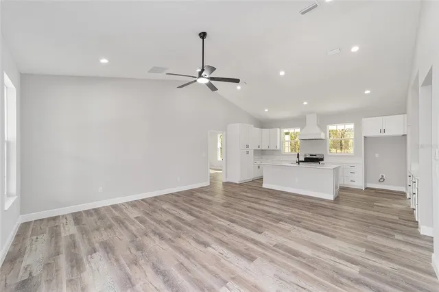 a view of kitchen with kitchen island stainless steel appliances refrigerator stove and wooden floor