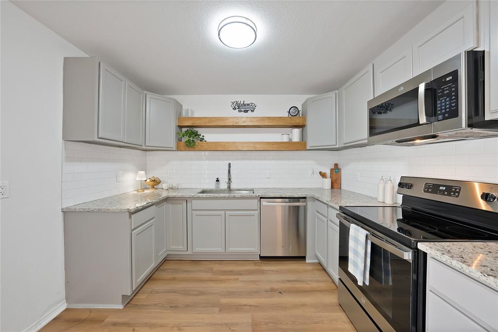 715 East Avenue F Midlothian, TX 76065 - Photo 7 of 33 a kitchen with stainless steel appliances and white cabinets
