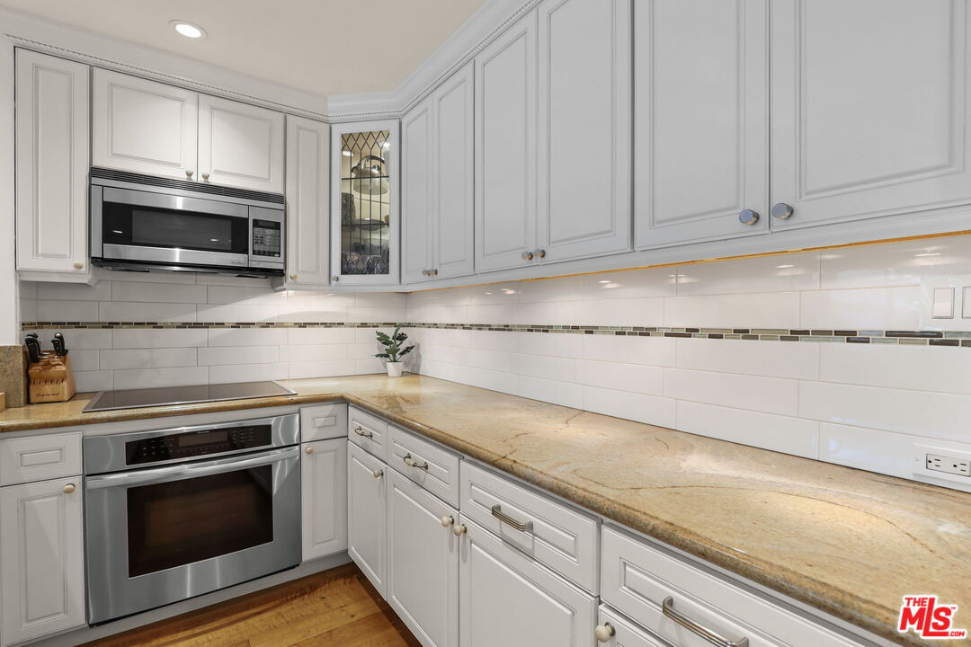 2170 Century Park East, Unit 104 Los Angeles, CA 90067 - Photo 11 of 42 a kitchen with granite countertop white cabinets and stainless steel appliances