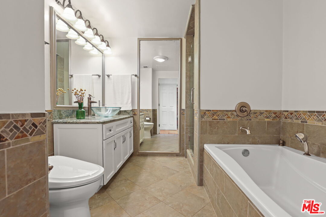 2170 Century Park East, Unit 104 Los Angeles, CA 90067 - Photo 18 of 42 a bathroom with a granite countertop sink mirror bathtub and toilet