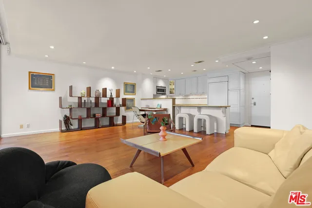 a living room with furniture and kitchen view with wooden floor