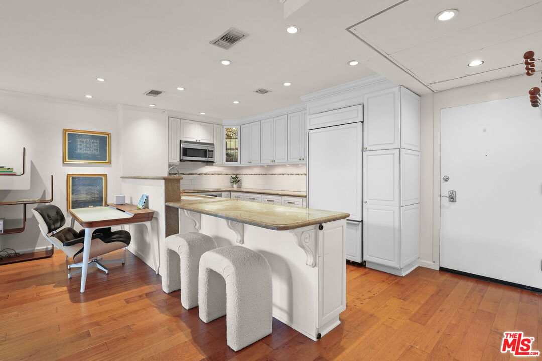 2170 Century Park East, Unit 104 Los Angeles, CA 90067 - Photo 8 of 42 a kitchen with kitchen island a stove a table and chairs in it
