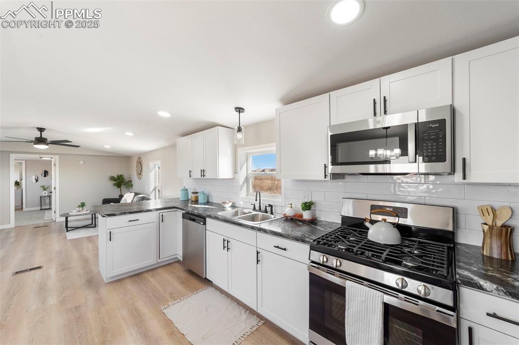 35275 Book Road Yoder, CO 80864 - Photo 8 of 30 a kitchen with stainless steel appliances a sink a stove a microwave a sink and cabinets