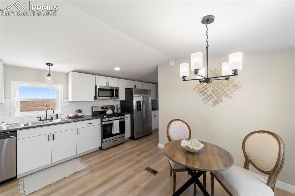 35275 Book Road Yoder, CO 80864 - Photo 10 of 30 a kitchen with stainless steel appliances granite countertop a stove a sink dishwasher a dining table chairs with wooden floor