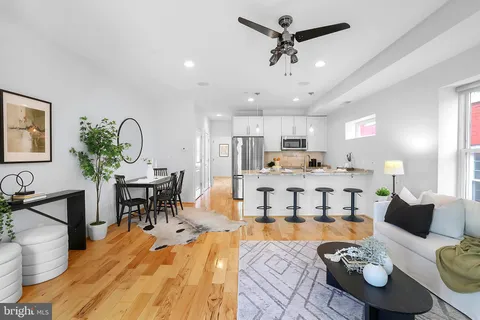 a kitchen with stainless steel appliances granite countertop a refrigerator a sink a stove a dining table and chairs