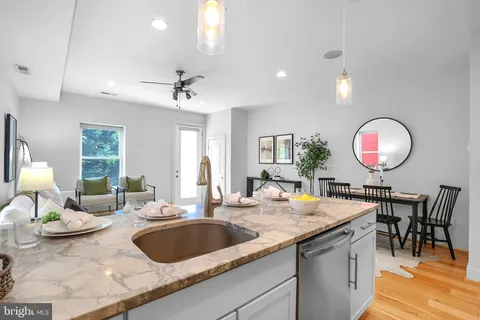 a living room with stainless steel appliances granite countertop furniture sink and wooden floor