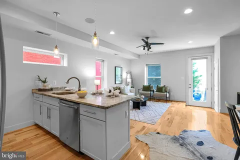 a kitchen with stainless steel appliances granite countertop a dining table chairs and white cabinets