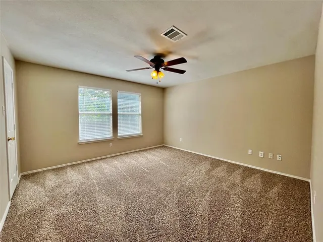 an empty room with windows and ceiling fan