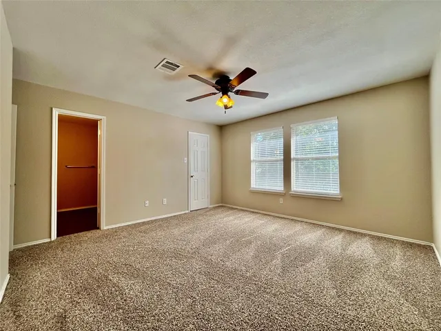 an empty room with windows and fan