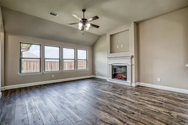 an empty room with wooden floor and a ceiling fan
