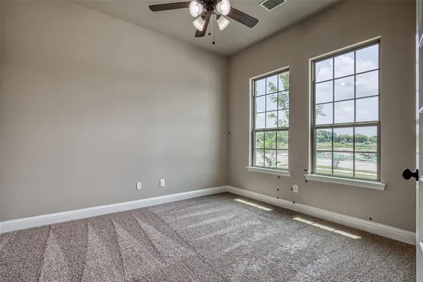 an empty room with a chandelier fan and windows
