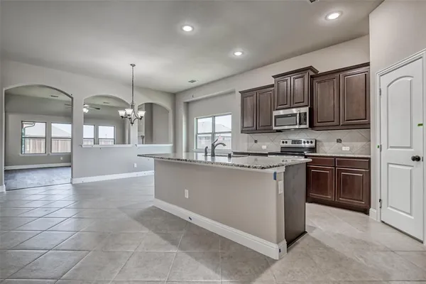a kitchen with granite countertop stainless steel appliances wooden floor and a sink