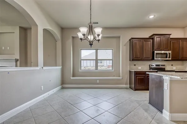 a living room with stainless steel appliances granite countertop furniture and a chandelier