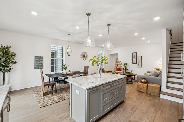 a open kitchen with stainless steel appliances granite countertop a white stove top oven a dining table and chairs with wooden floor