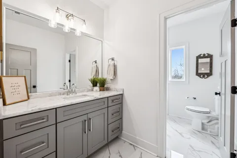 a bathroom with a granite countertop sink a toilet and a mirror