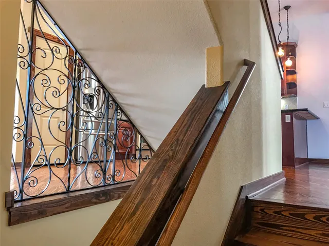 a view of a room with a hanging light and hardwood floor