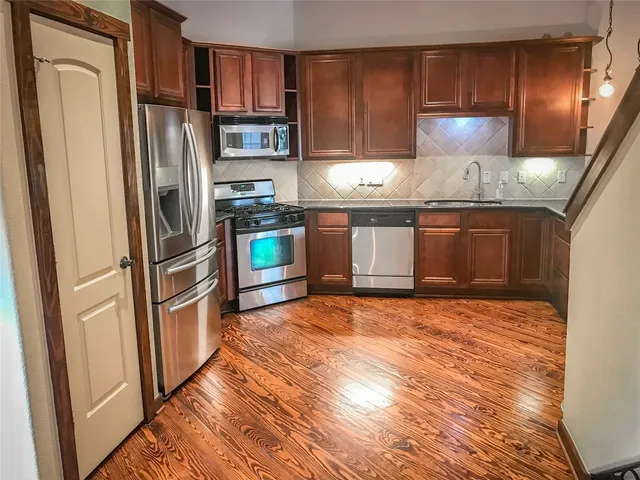 a kitchen with stainless steel appliances granite countertop a refrigerator stove and sink