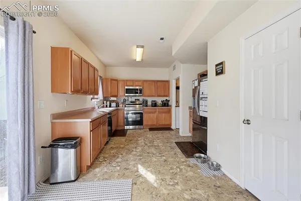 a kitchen with granite countertop a refrigerator and a stove top oven