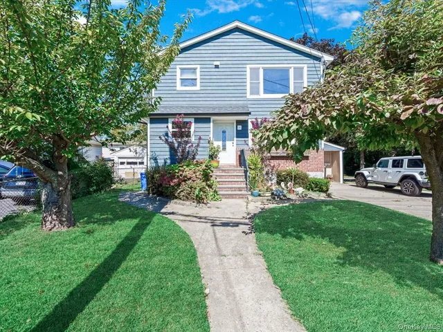 a front view of a house with a garden and trees