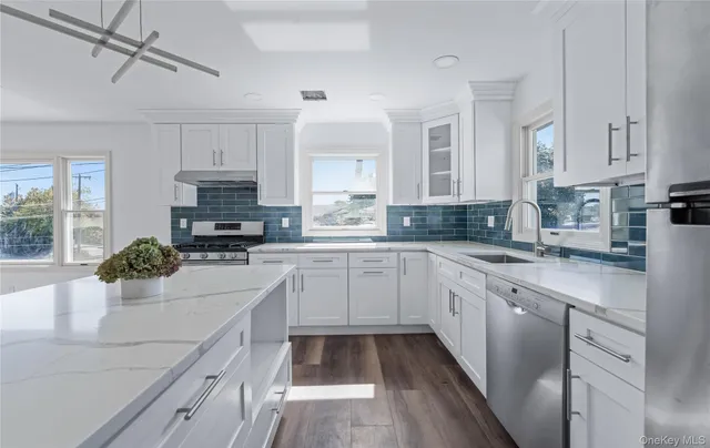 a kitchen with stainless steel appliances a sink a stove a refrigerator cabinets and a window