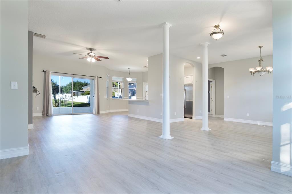 2560 Tall Maple Loop Ocoee, FL 34761 - Photo 9 of 32 a view of an empty room and a kitchen with wooden floor