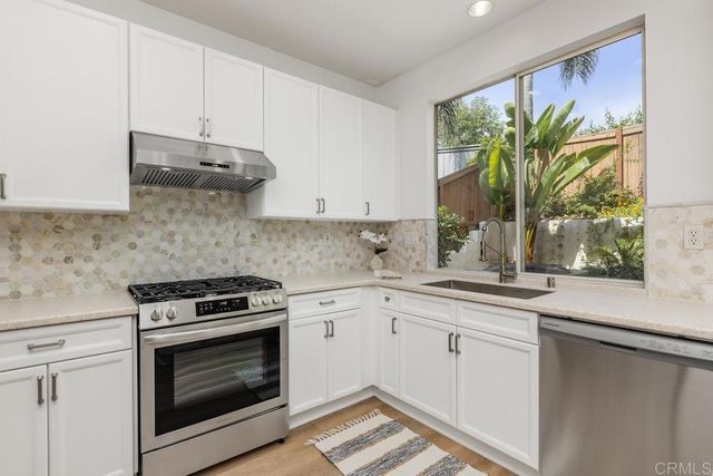 a kitchen with stainless steel appliances white cabinets and a stove top oven