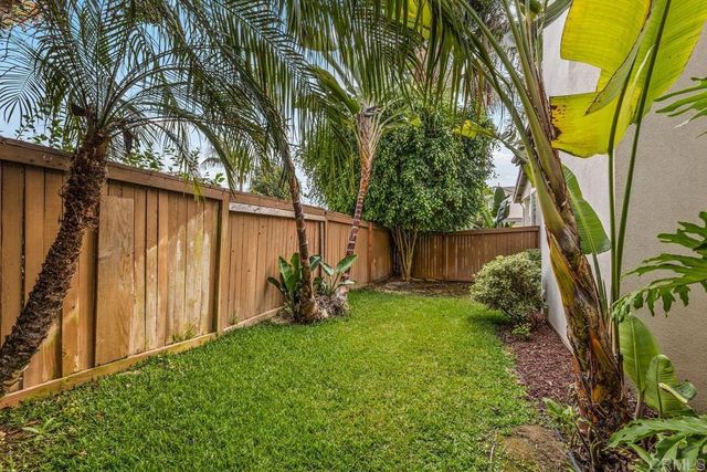 a view of backyard with potted plants and wooden fence